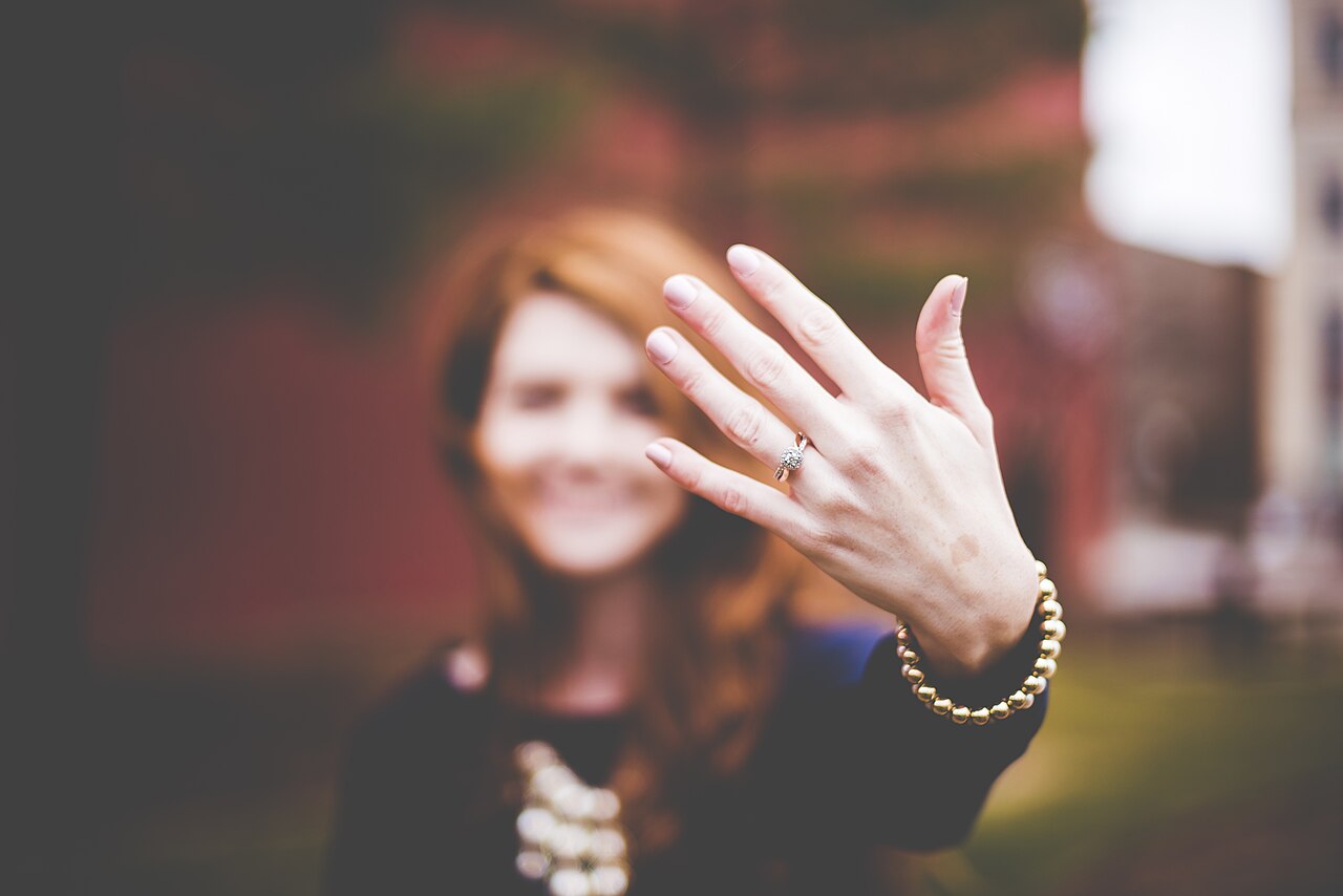 A woman holding out her hand to show a diamond engagement ring