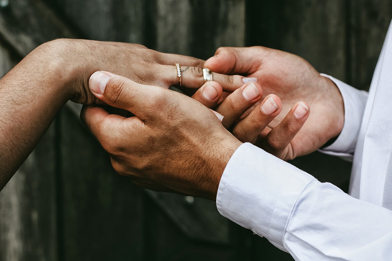 One person sliding a ring onto another person’s finger