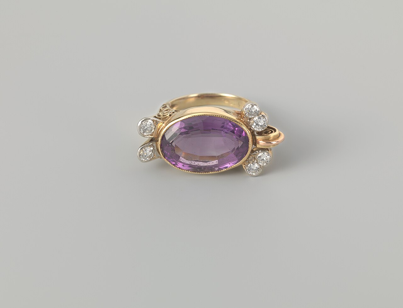 A gold ring set with an oval purple stone and small diamonds at each end